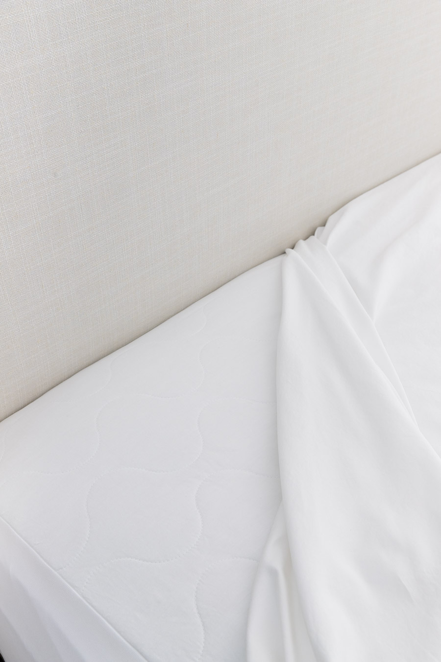 Waterproof mattress pad on bed under sheets