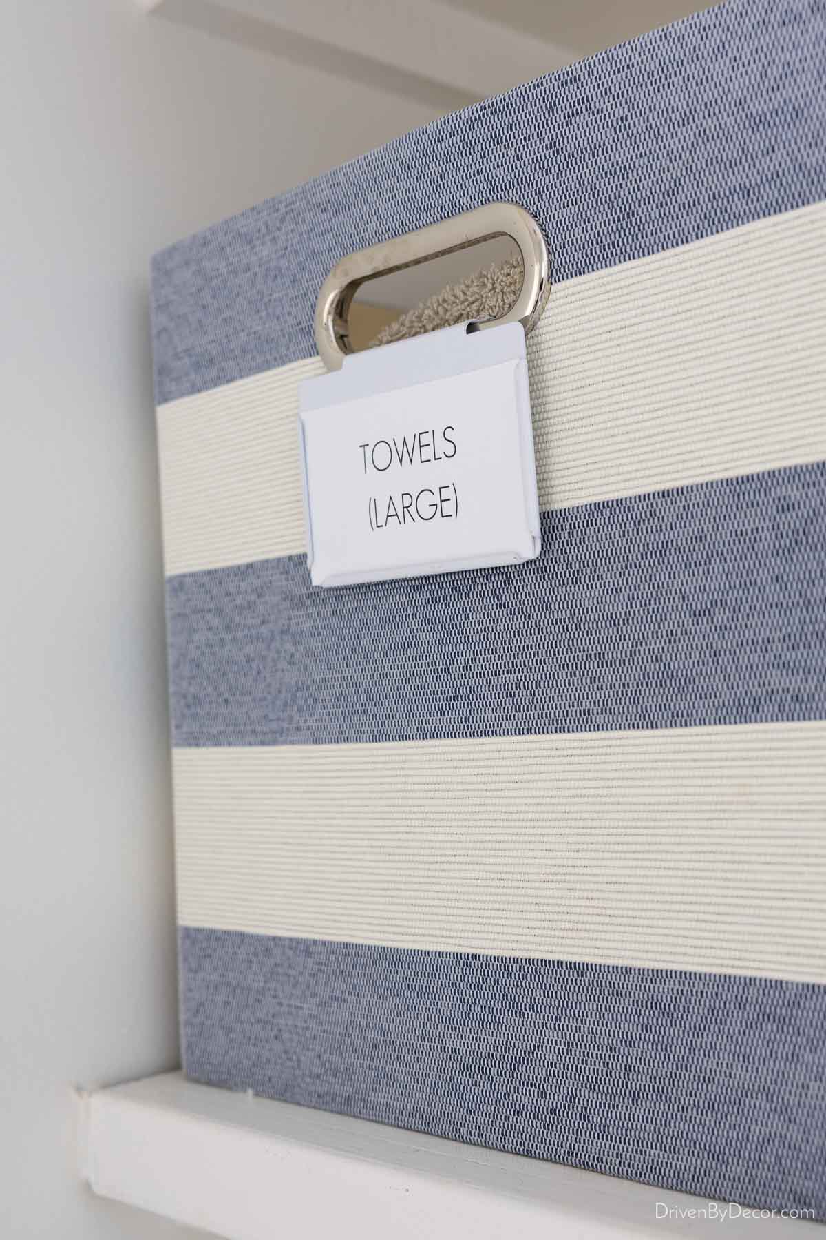 Blue and white striped bin with clip on label for towels