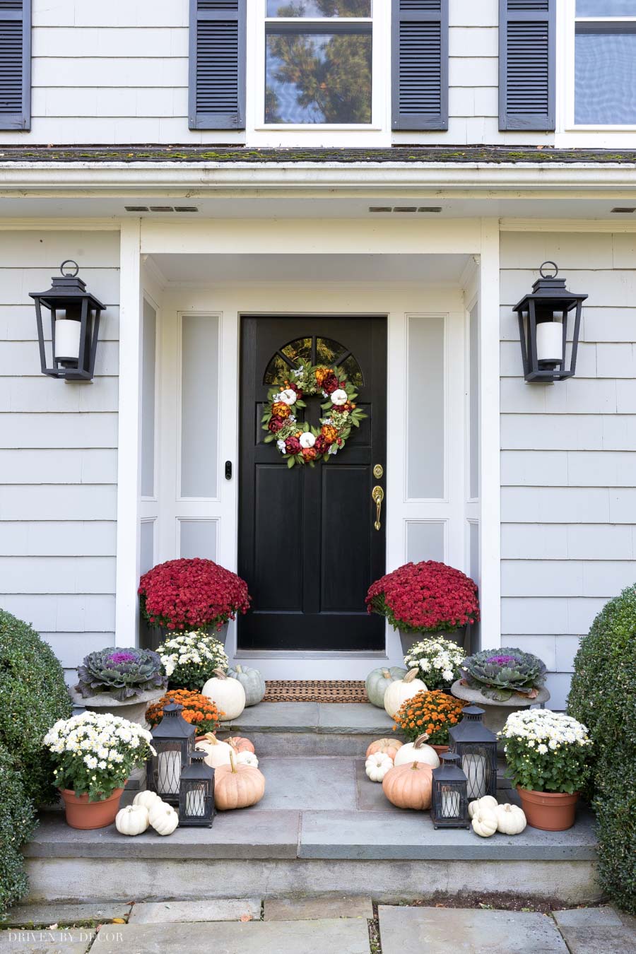 Love this look for a fall front porch! Pumpkins, mums, and lanterns line the steps!