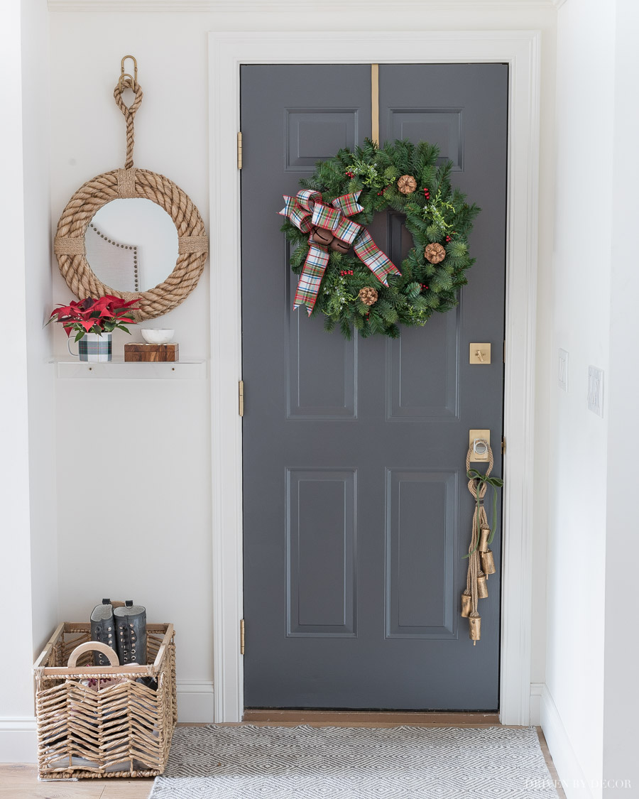 A Christmas wreath with plaid bow and bells and bells on a rope door hanger are perfect for decorating the door we go in and out of every day!