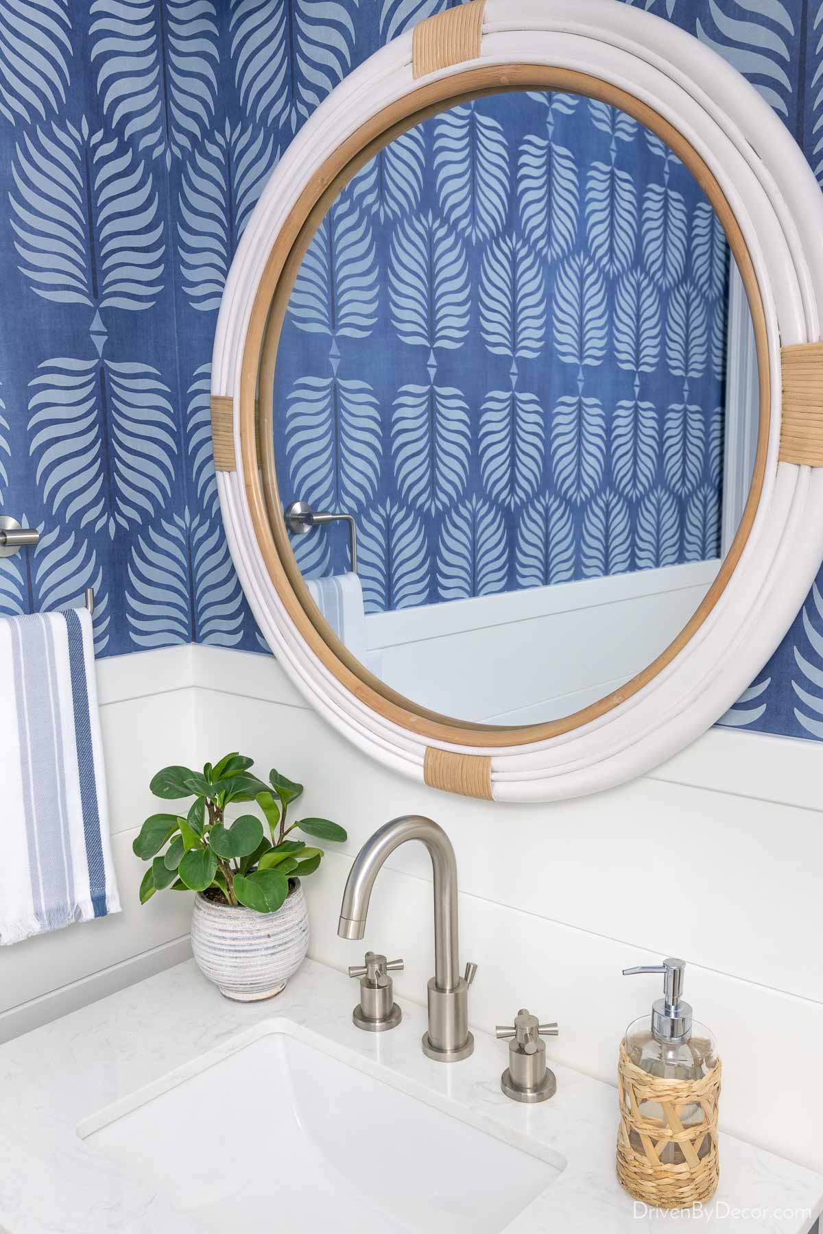 Round white rattan mirror above sink in powder room