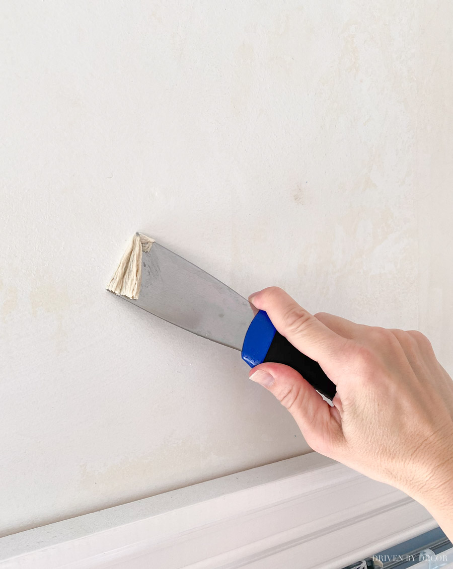 Using a putty knife to remove excess wallpaper glue