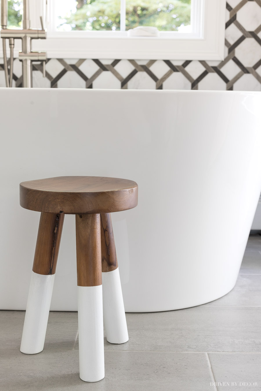 The cutest wood stool by the freestanding tub in this master bathroom