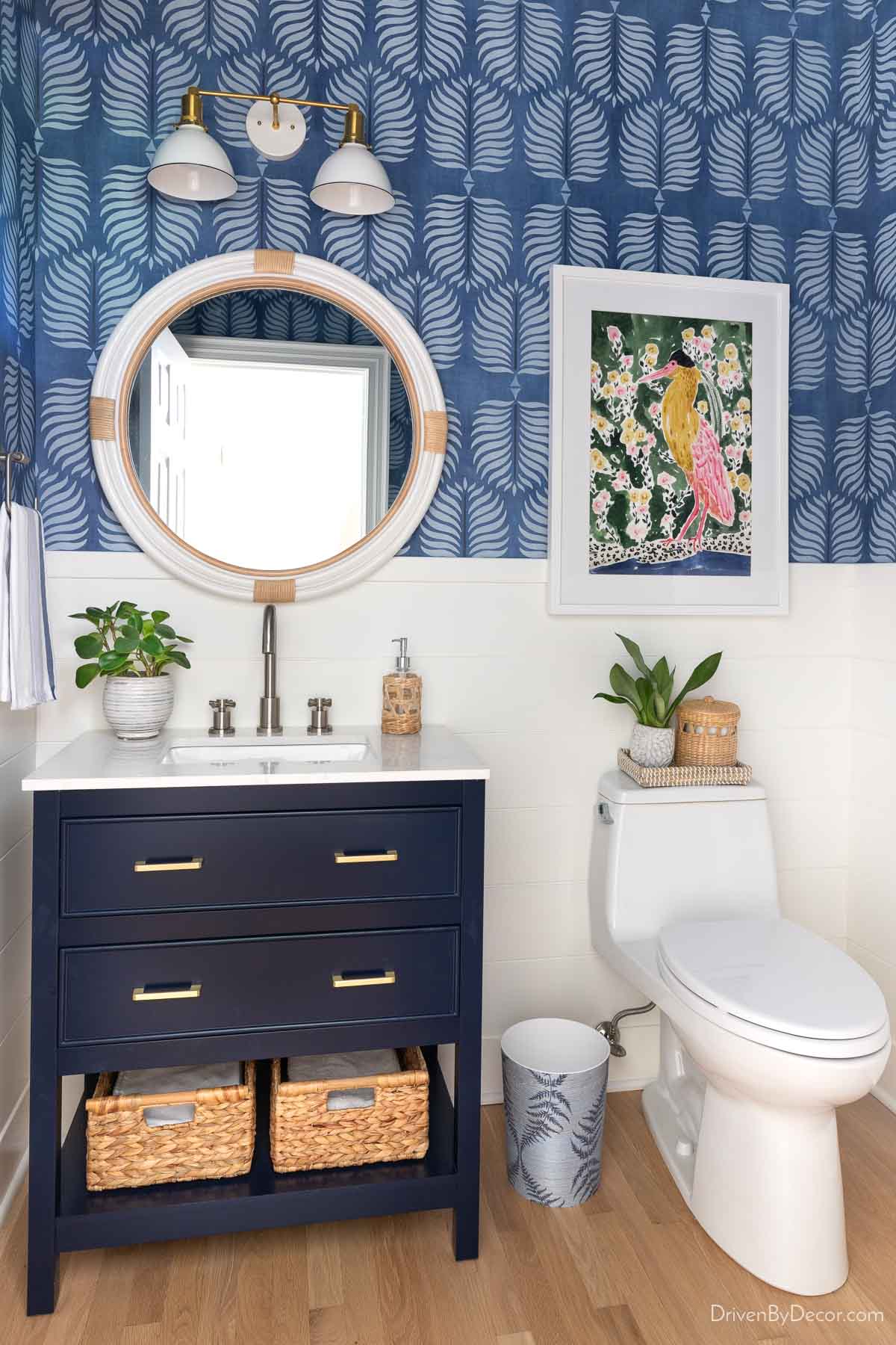 Full view of bathroom with two-light brass and white sconce over round mirror