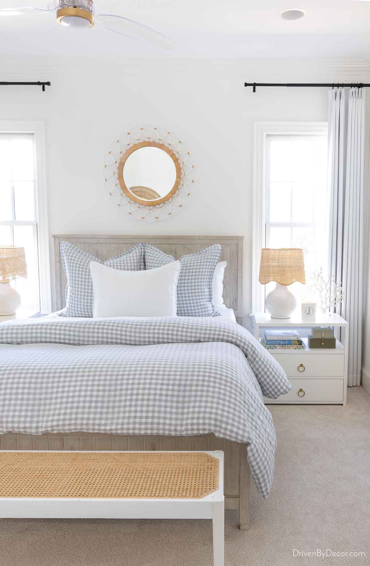 Woven round mirror above a queen bed