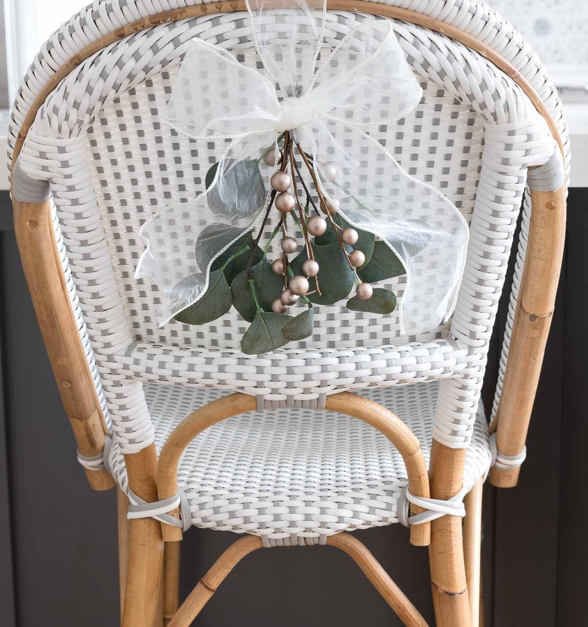 Mini greenery swags tied with a bow are the perfect simple Christmas decorations for the backs of our chairs