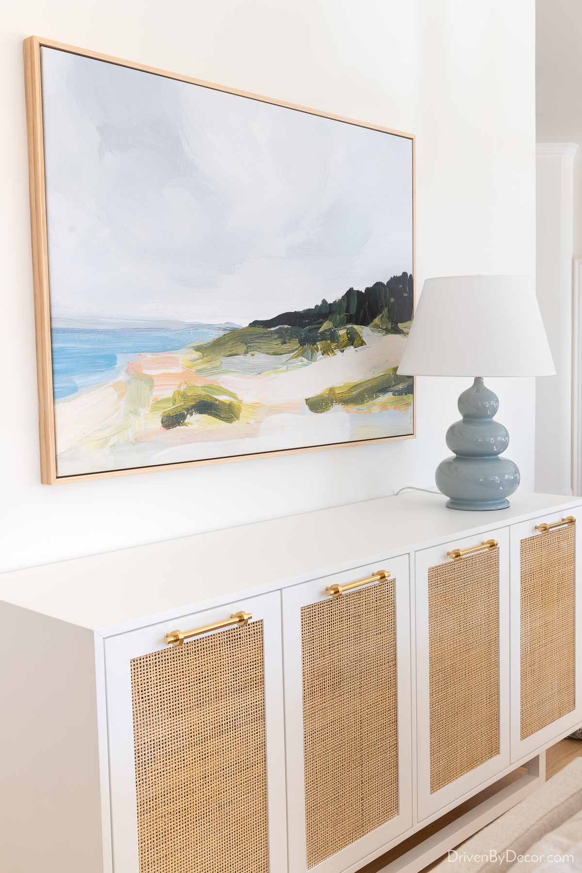 Cane sideboard, large canvas art print, and blue gourd lamp in dining room