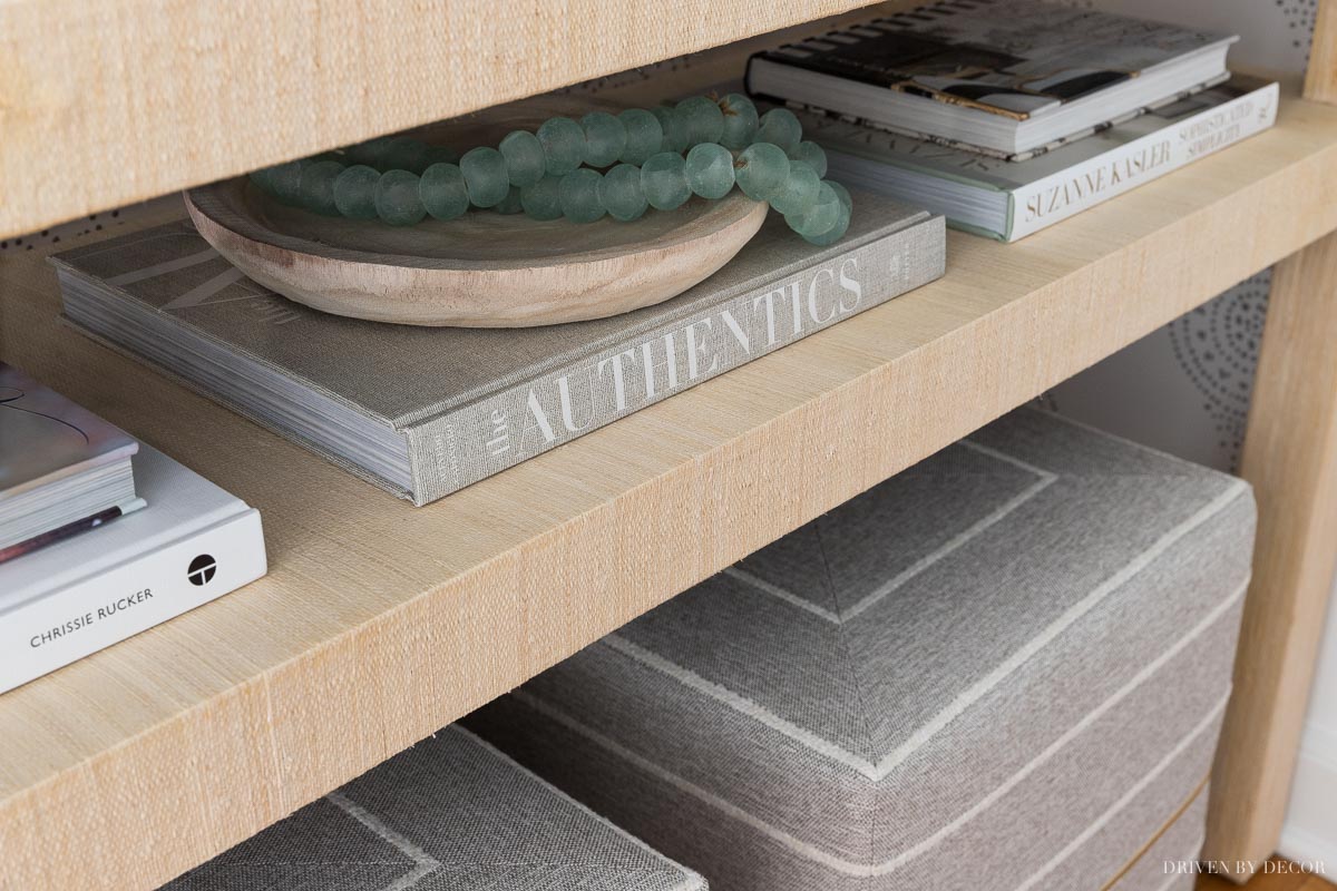 Entryway console table accessories - books, a shallow wood bowl, and glass beads