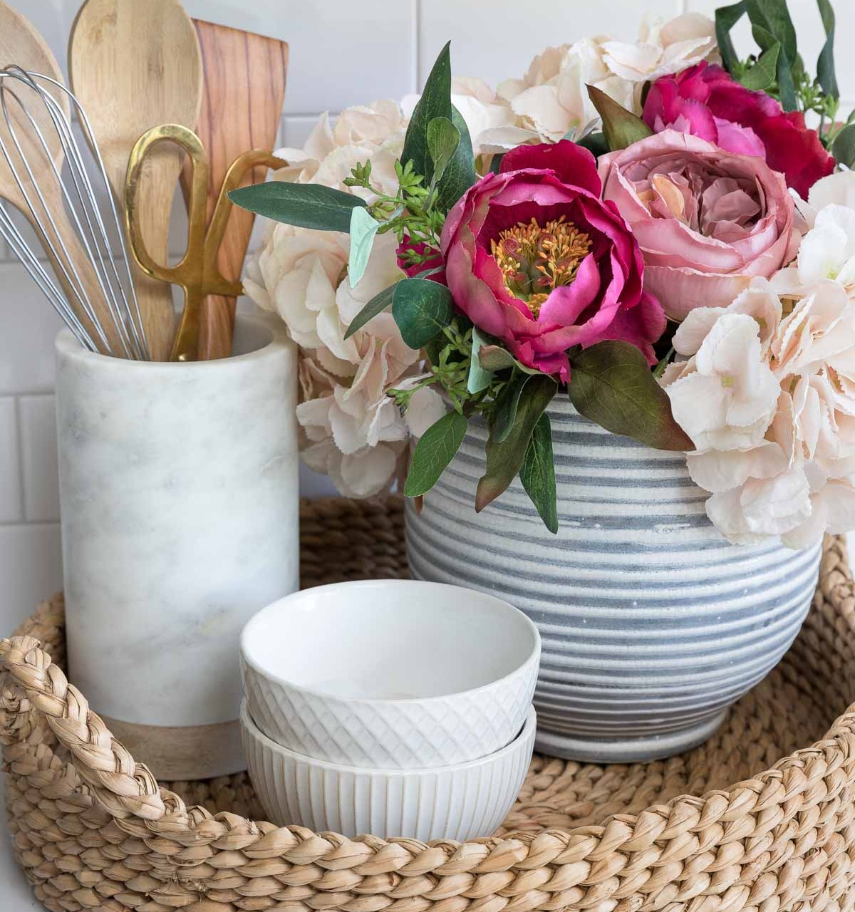 The artificial flowers in our kitchen sitting in a round woven tray