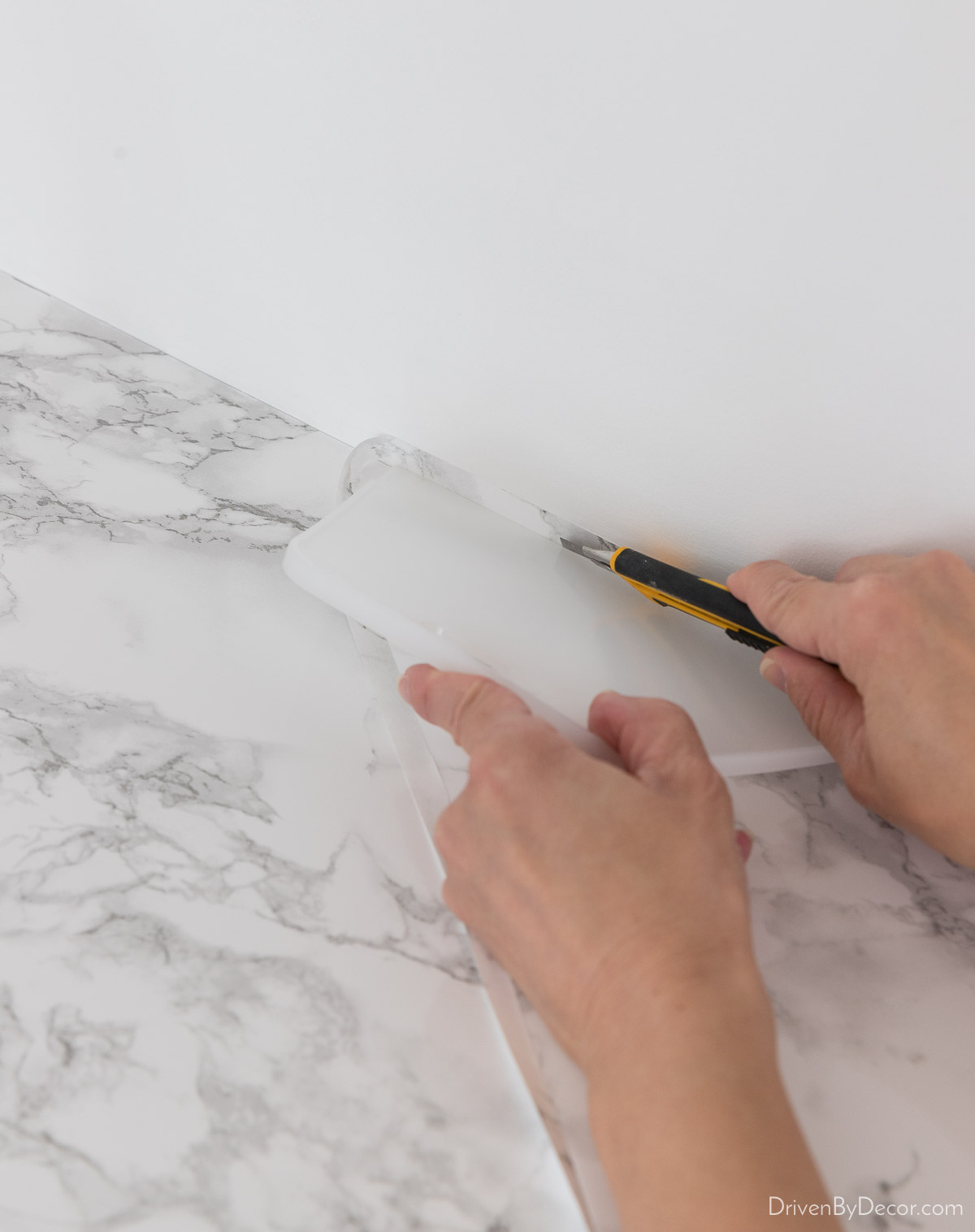 Use a smoothing tool and utility knife to cut off extra marble contact paper