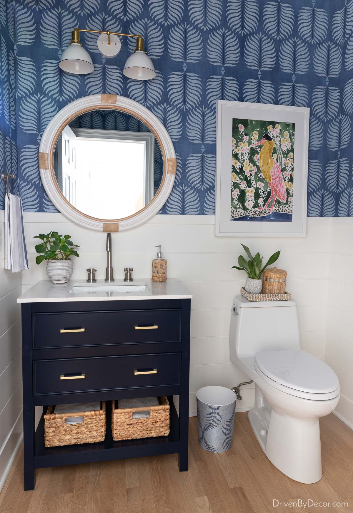 Bathroom with shiplap walls, wallpaper, small vanity, and round mirror