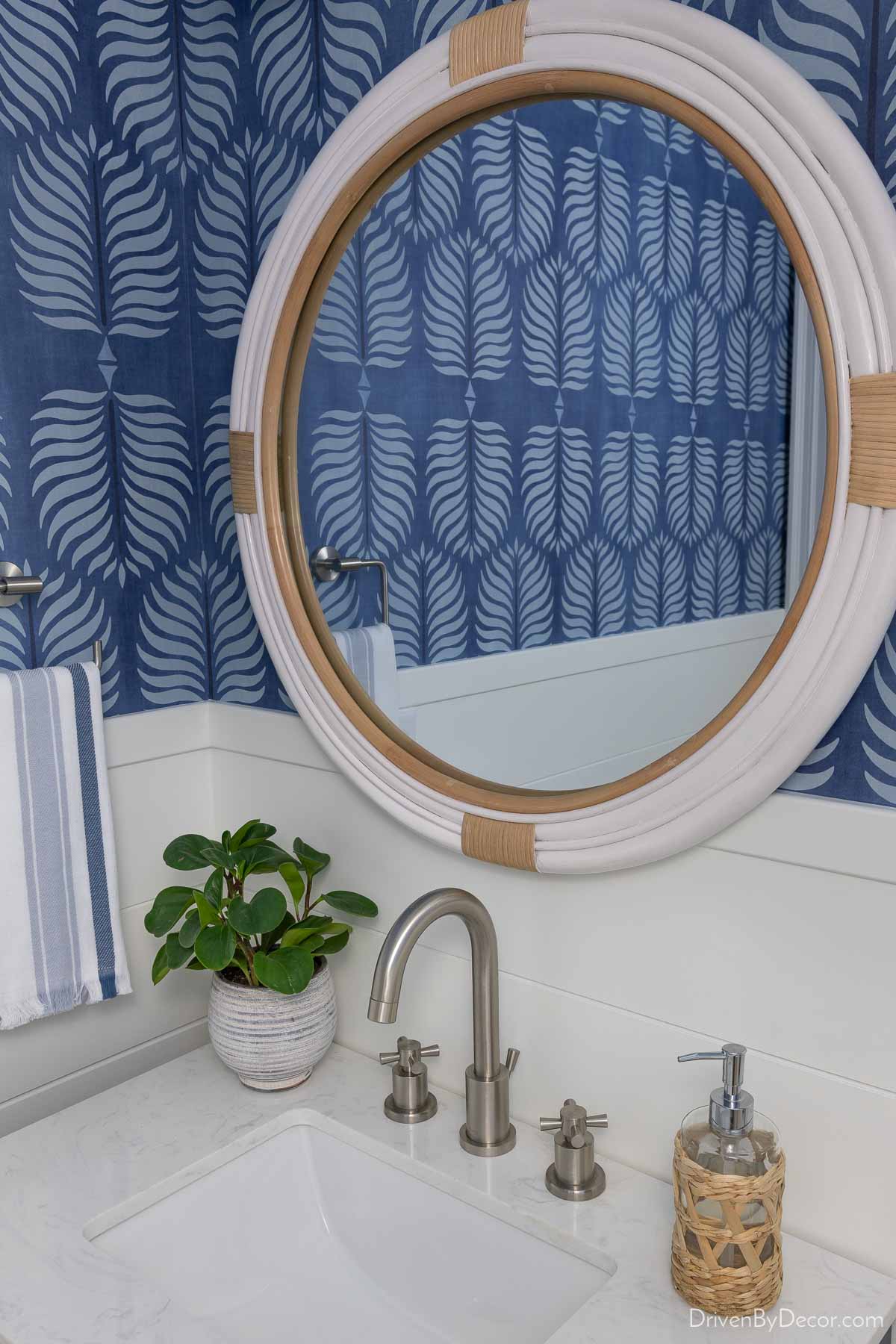 White round rattan mirror overlapping the shiplap in our hall bathroom