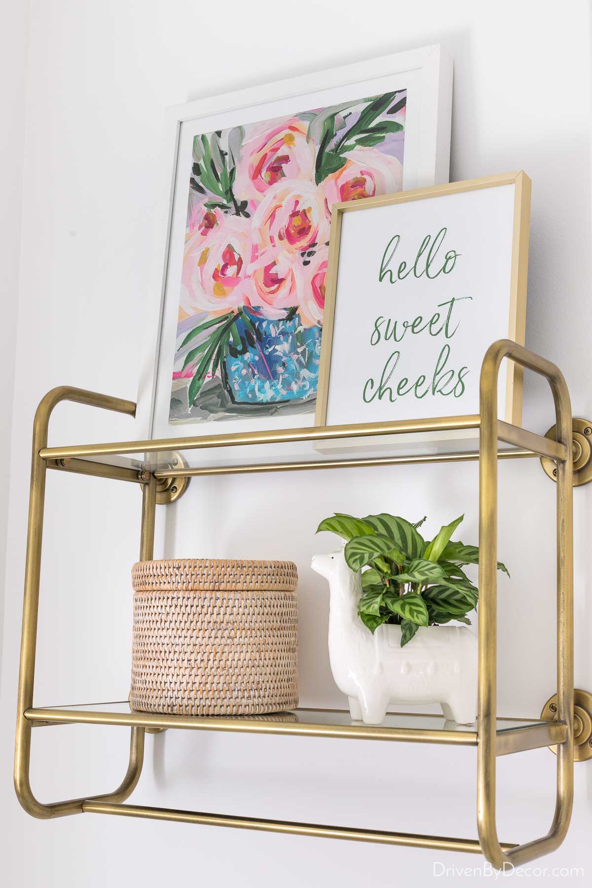 Brass and glass open shelving over the toilet