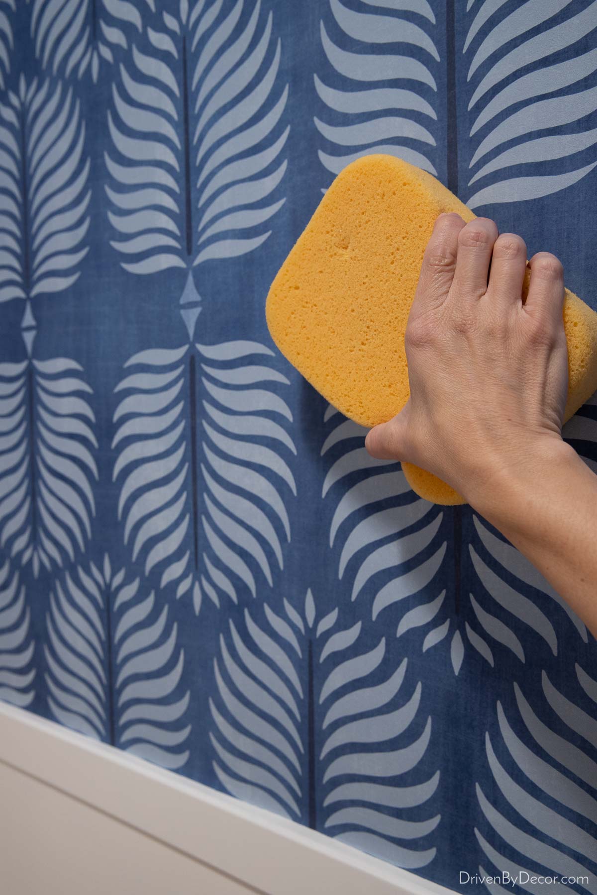 Using sponge to wipe of excess wallpaper glue 