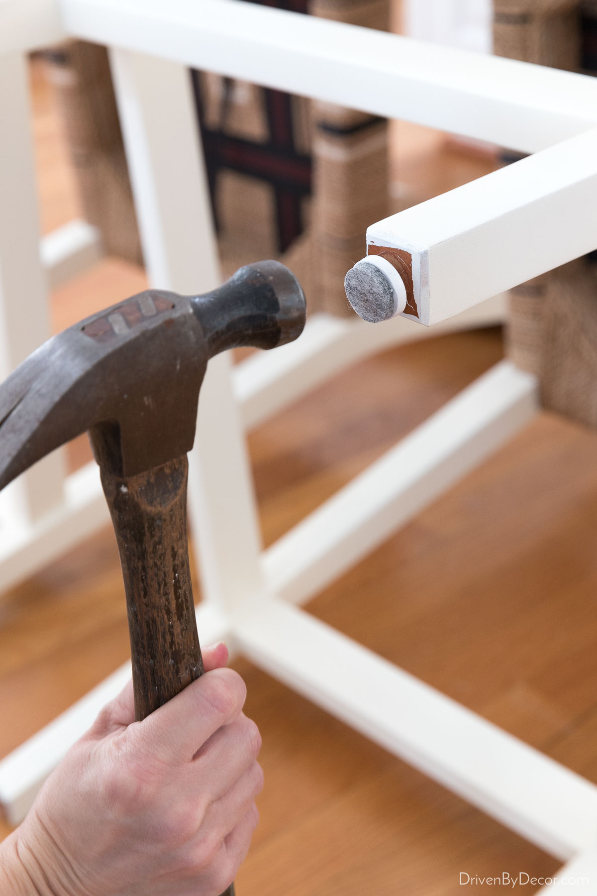 Nailing felt pads onto the feet of chairs to protect hardwood floors