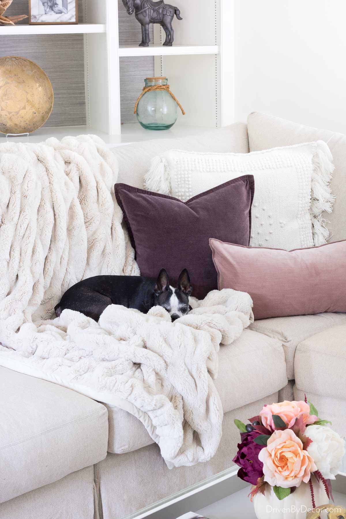 A cozy faux fur throw and velvet pillows on sofa for fall