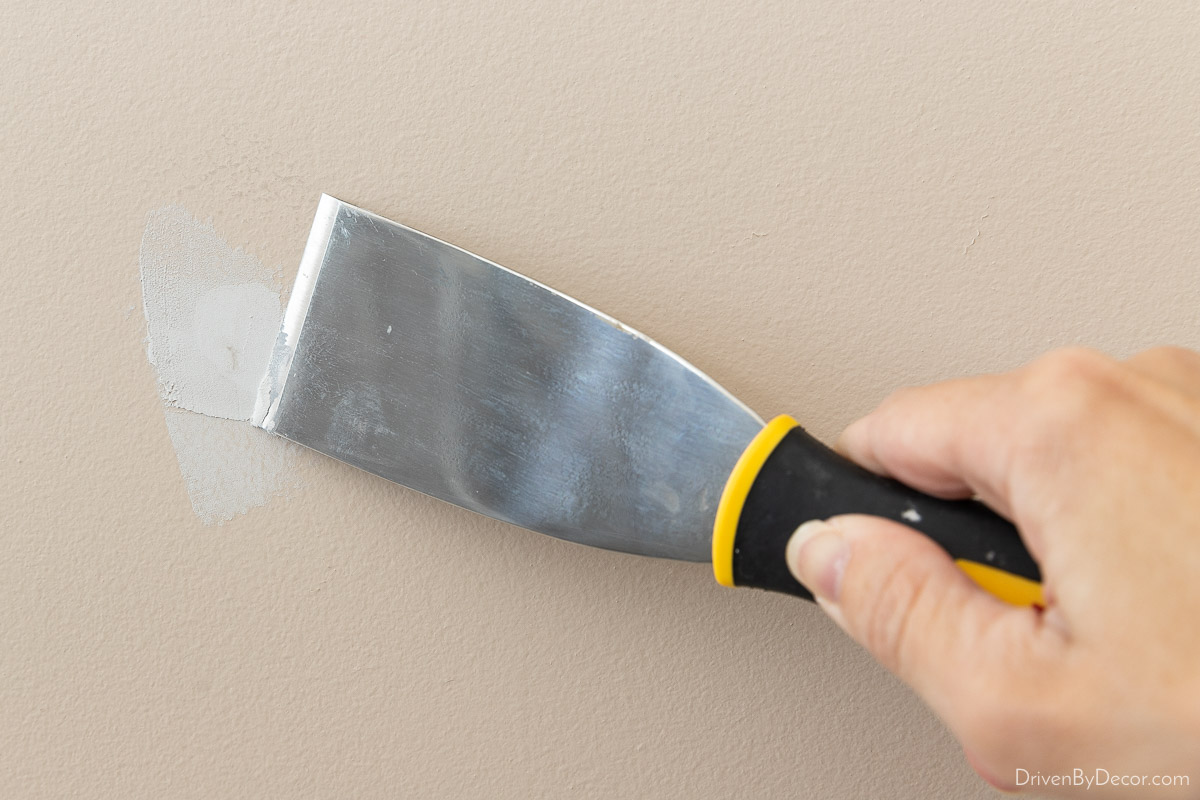 Using a putty knife and spackling to fix small hole in the wall