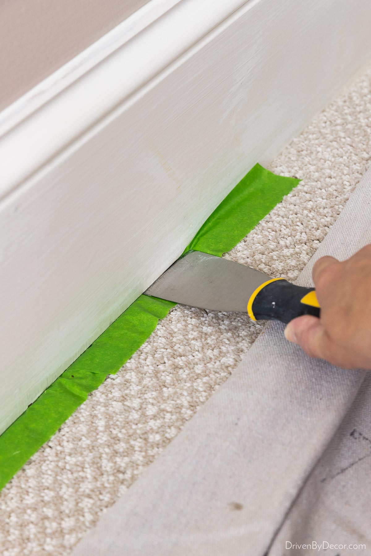 Place painter's tape under baseboard to protect flooring