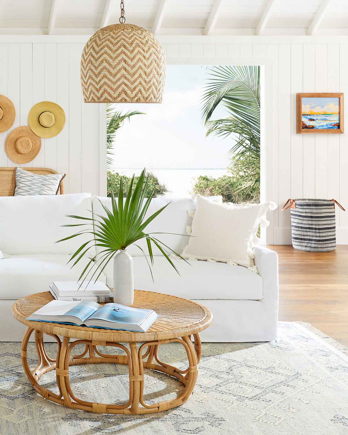 Gorgeous round rattan coffee table with patterned blue rug and white sofa