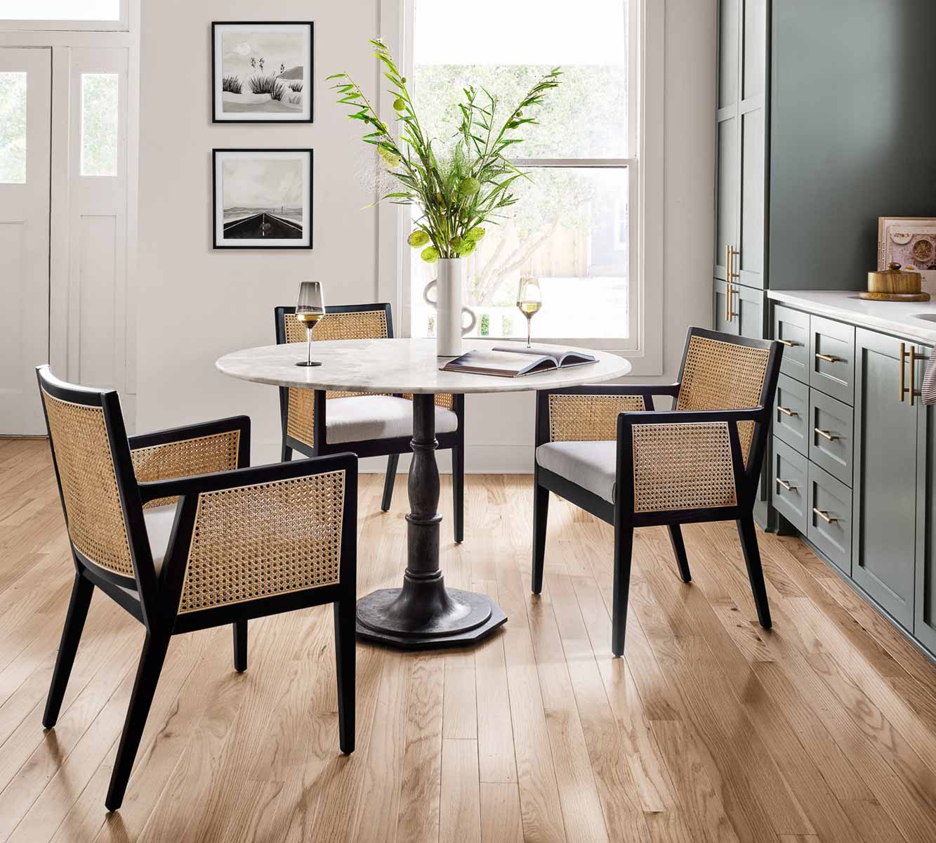 Three black cane dining chairs around round table