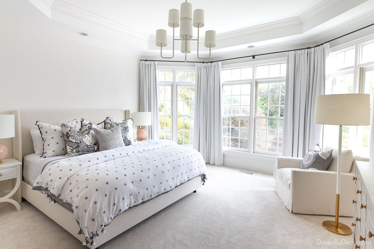 Primary bedroom with bedside lamps, floor lamp by chair, and chandelier with shades