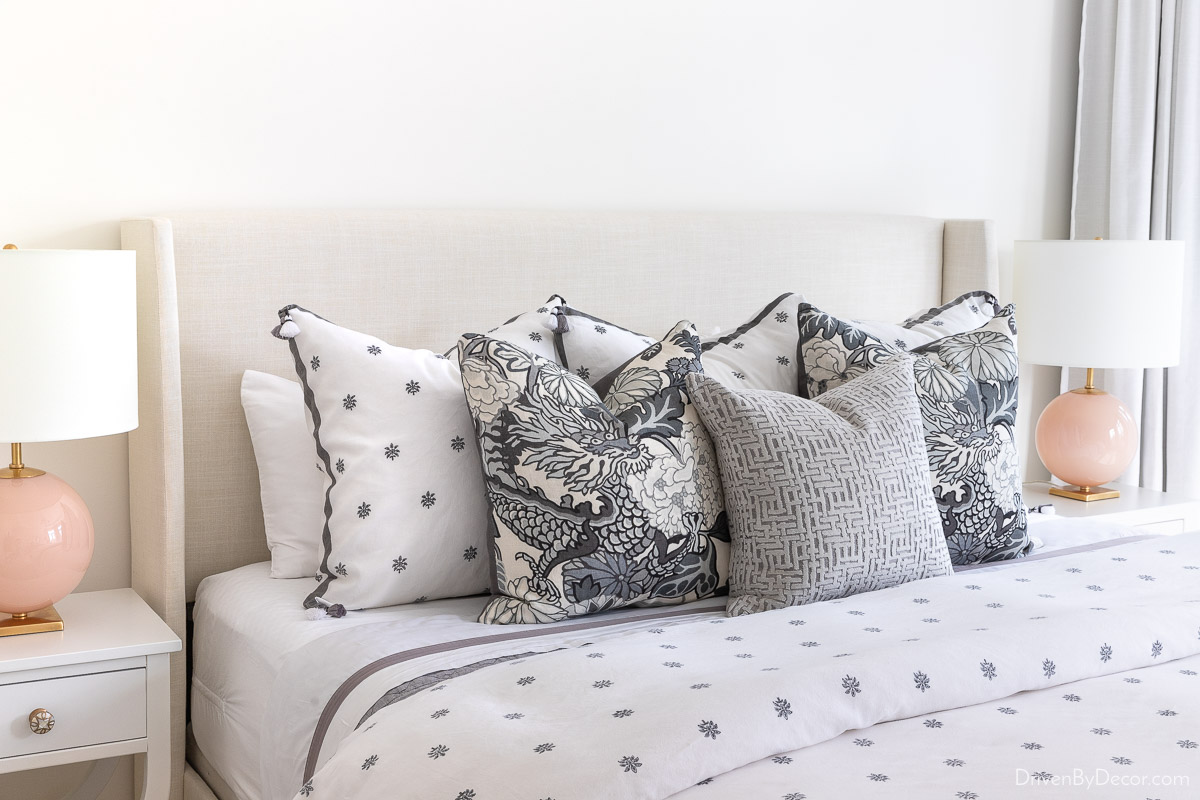 Round blush bedside lamps on both sides of an upholstered bed