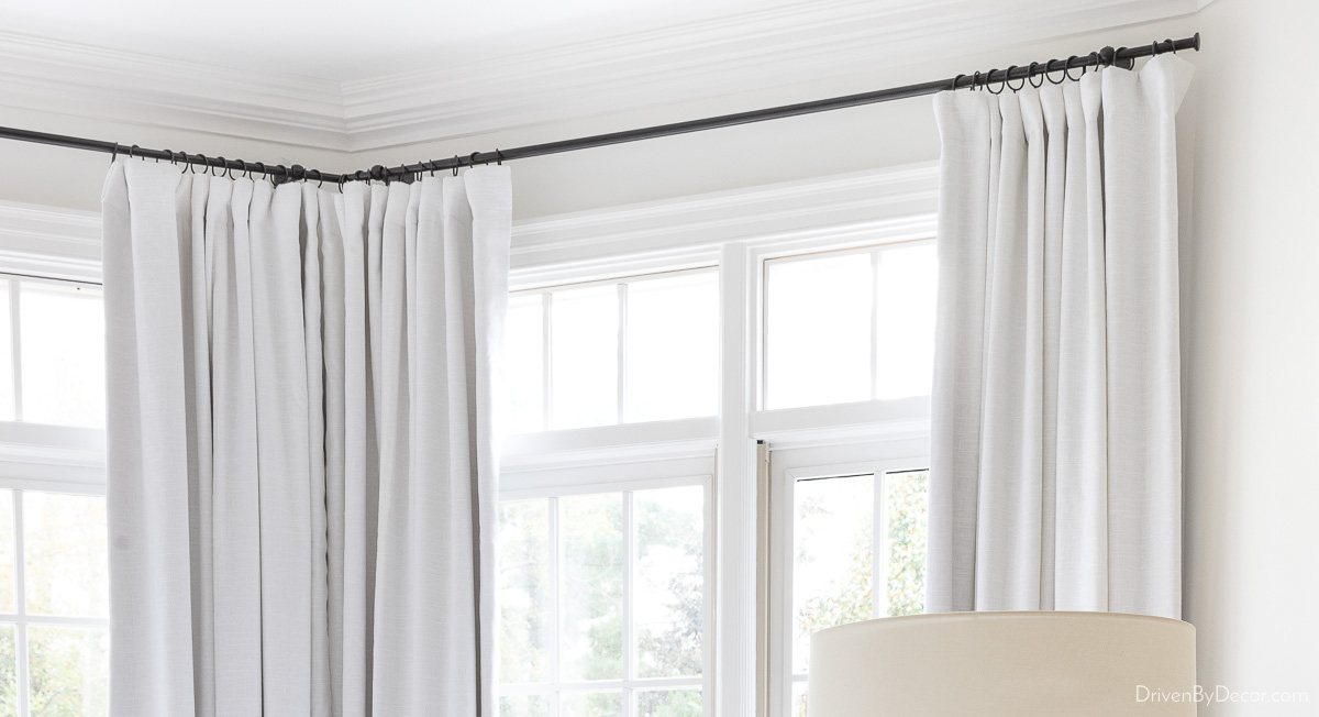 Corner curtain rod holding white curtains