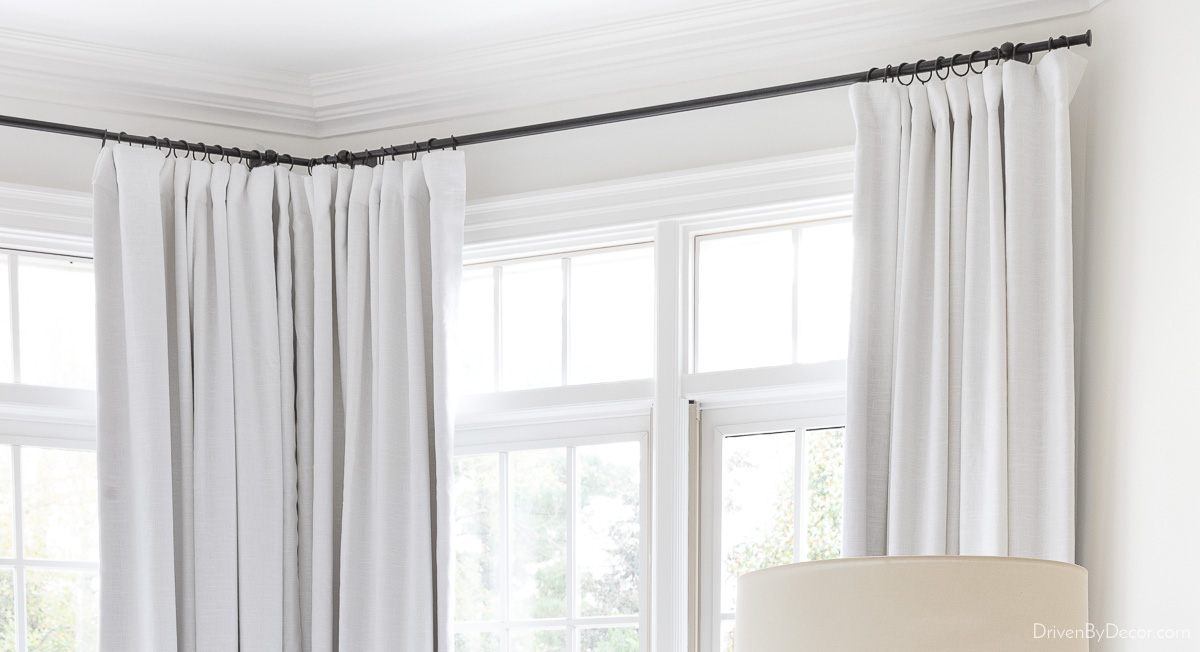 Corner curtain rod holding white curtains