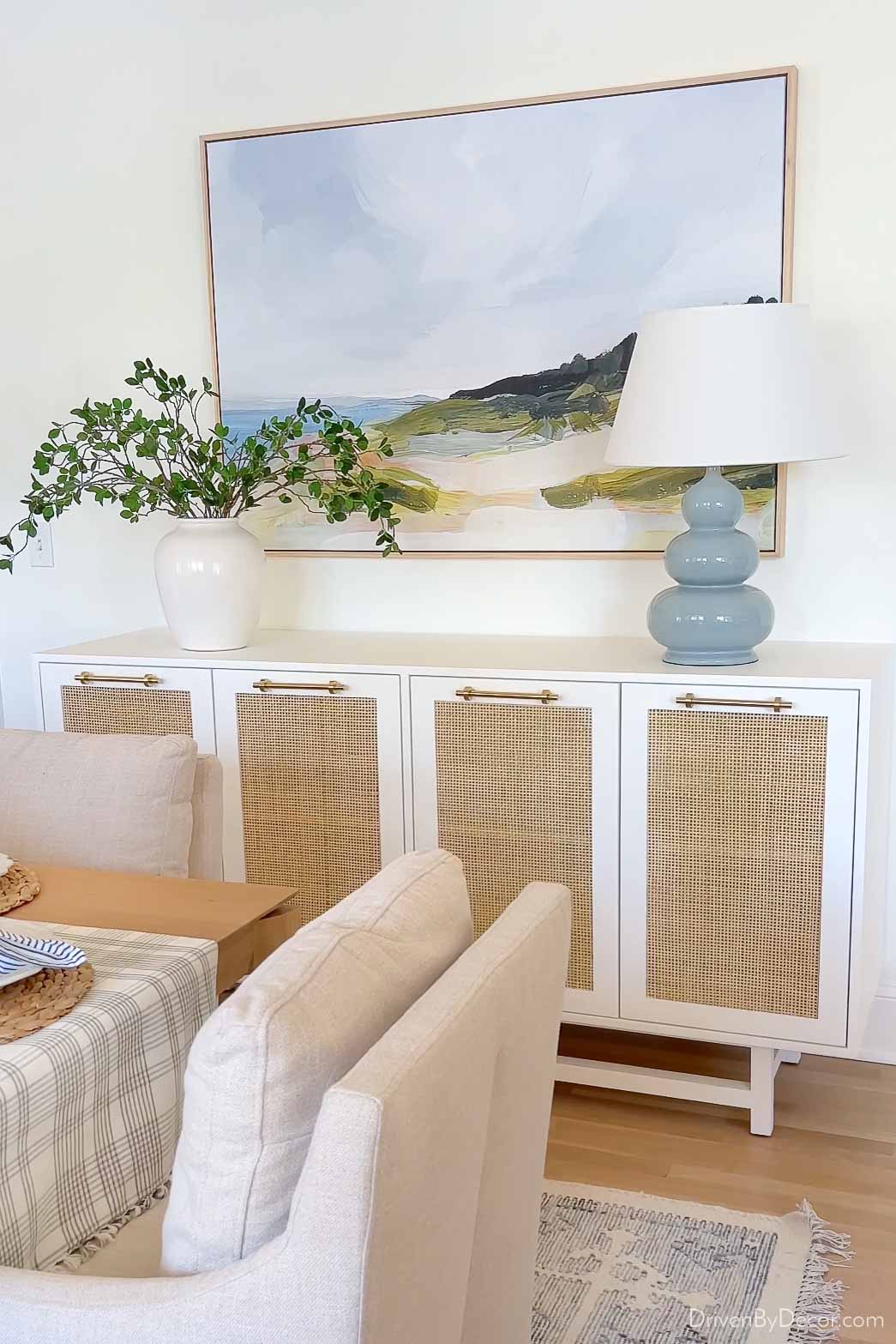 Dining room sideboard with table lamp, art, and vase with greenery