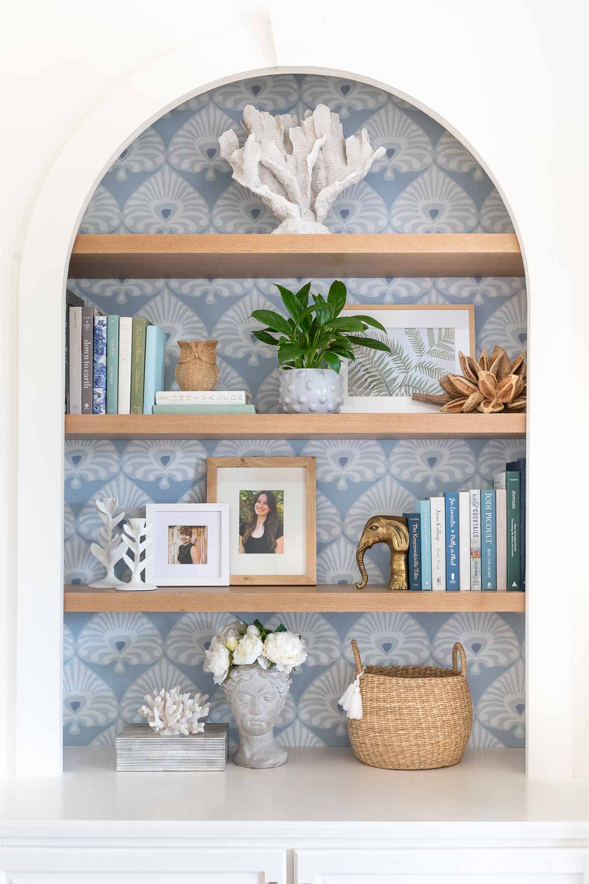 Bookshelf decor on oak shelves with wallpaper on back of bookcase