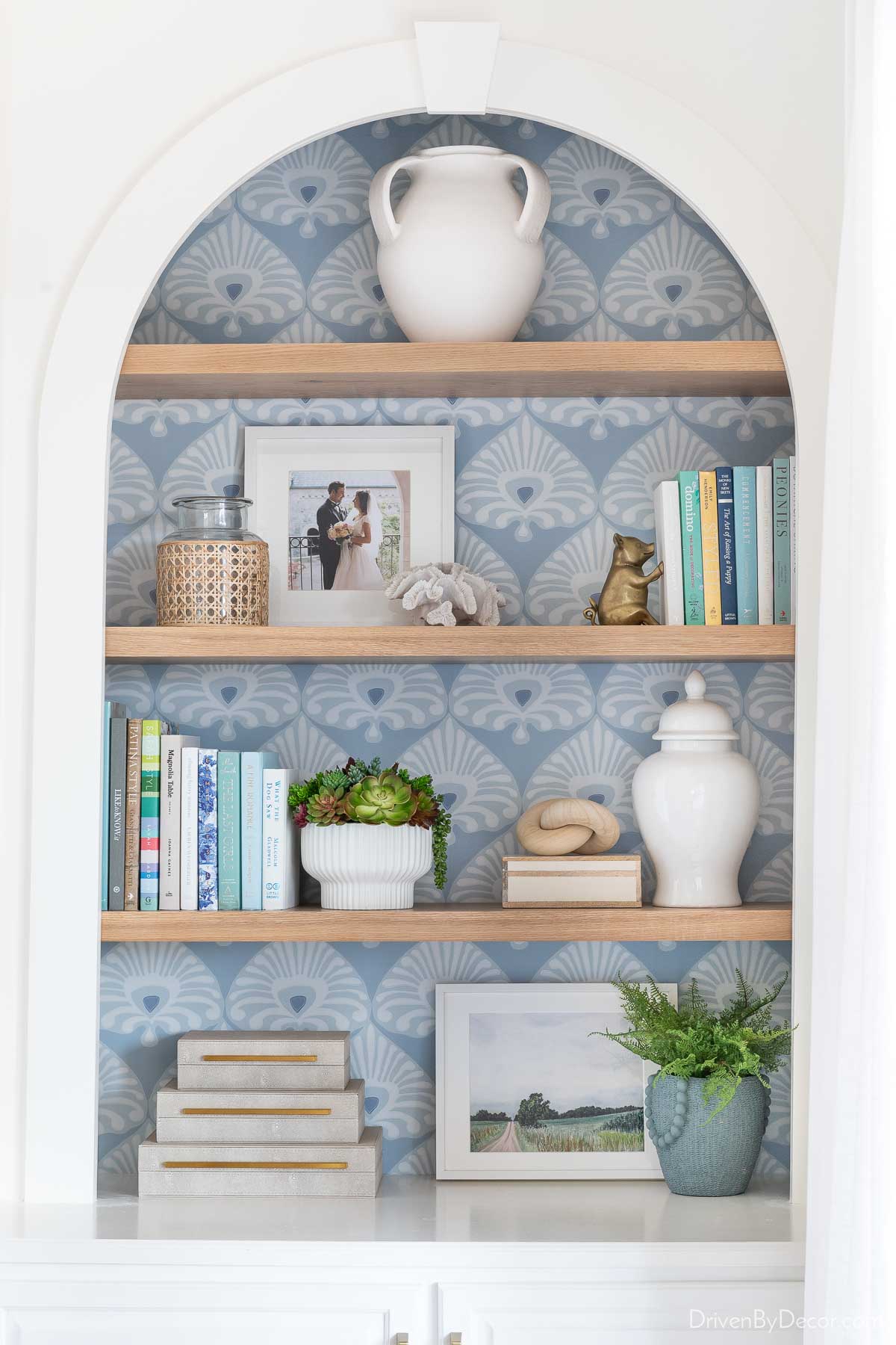 Bookshelf styling on oak shelves with wallpaper on back of bookcase