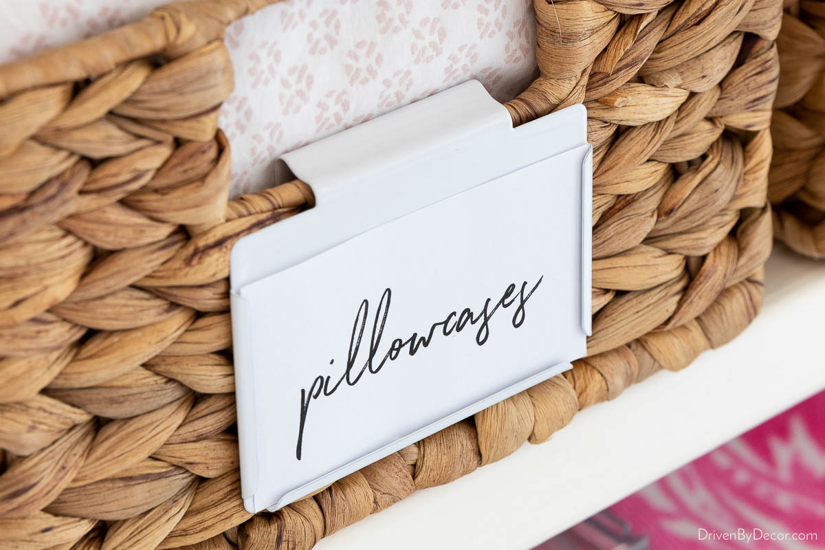 White bin clips to label baskets in linen closet