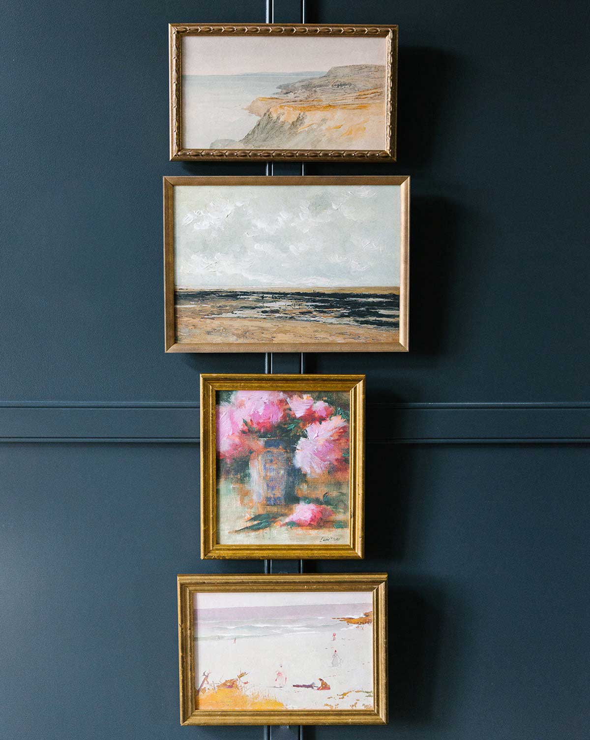 A gallery wall of four framed art pieces in a vertical stack