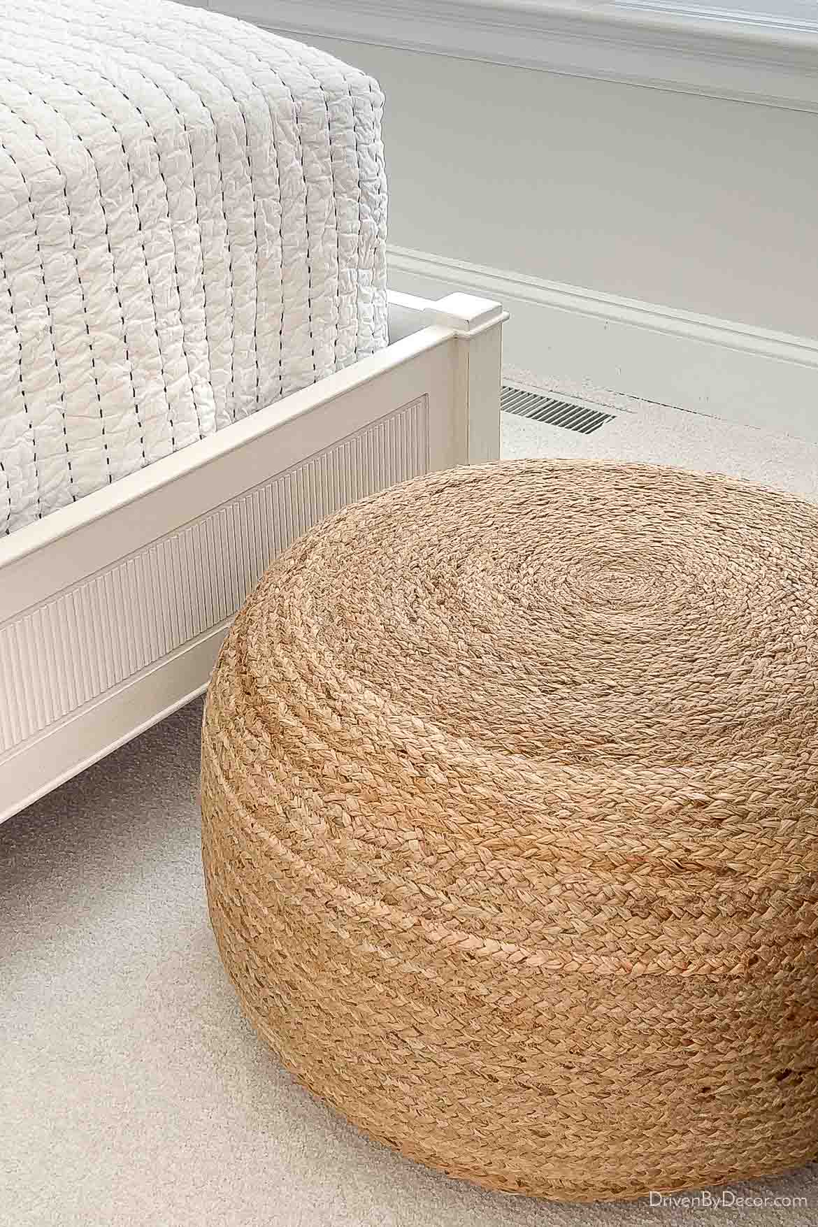Large jute pouf at the end of a twin bed as coastal bedroom decor