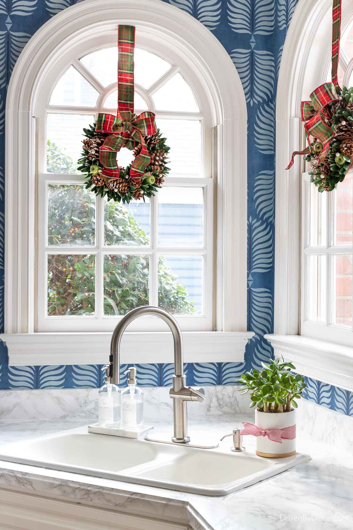 Mini Christmas wreaths layered over kitchen windows