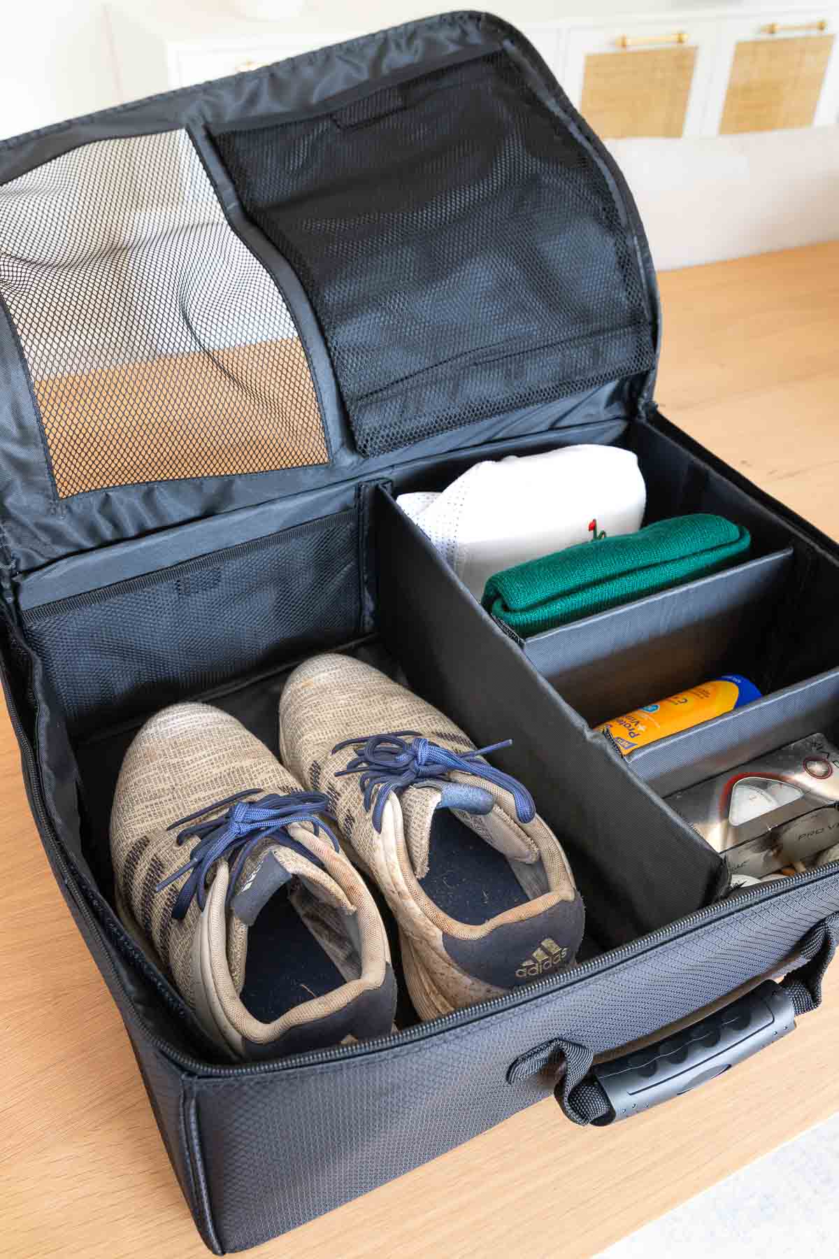 Golf trunk organizer with golf shoes, hats, balls, and tees stored inside