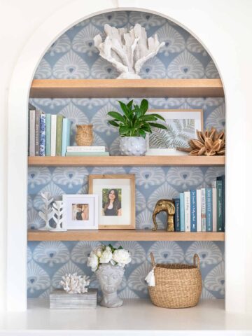 Oak shelves on a bookcase with wallpapered background