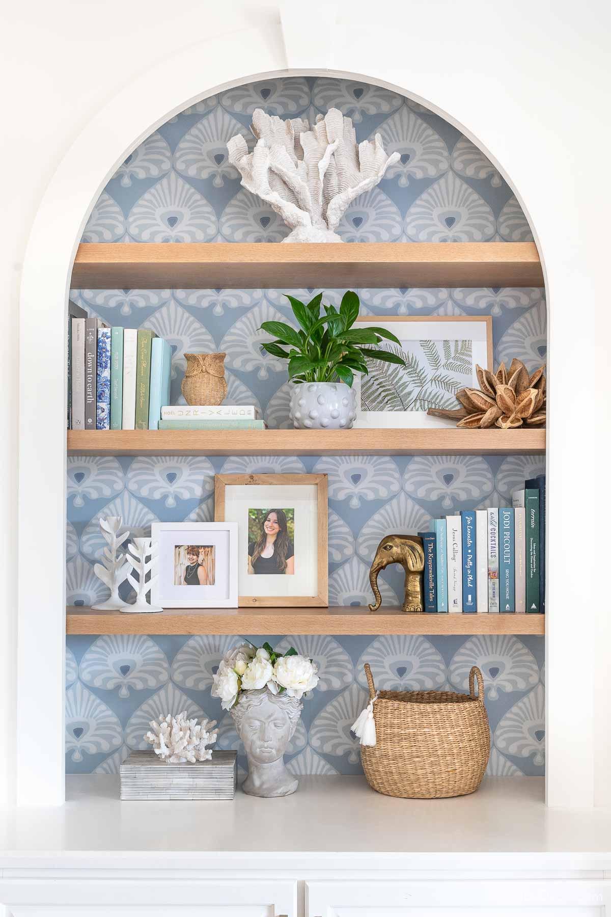 Oak shelves on a bookcase with wallpapered background