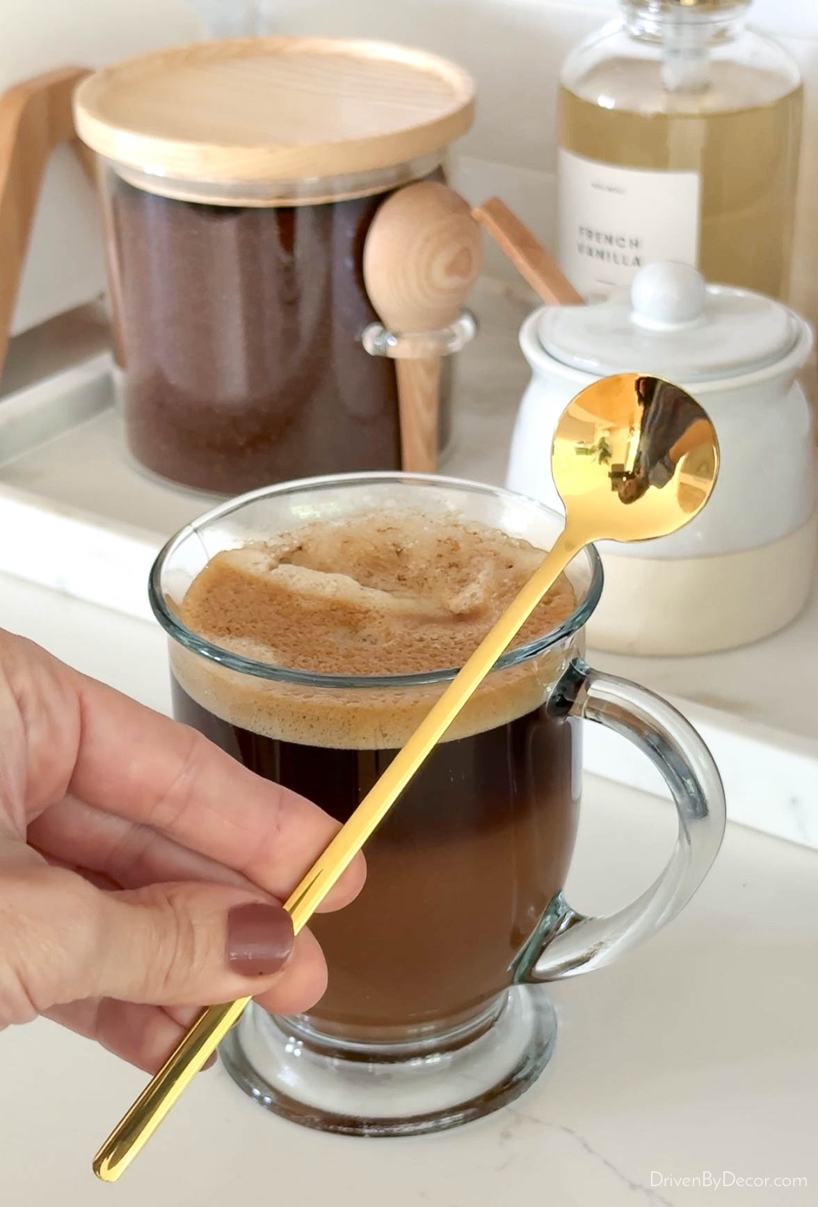 Long handled gold spoon in front of coffee cup