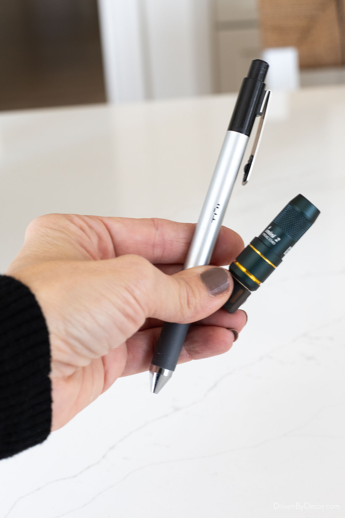 Mini flashlight held up next to pen for size comparison