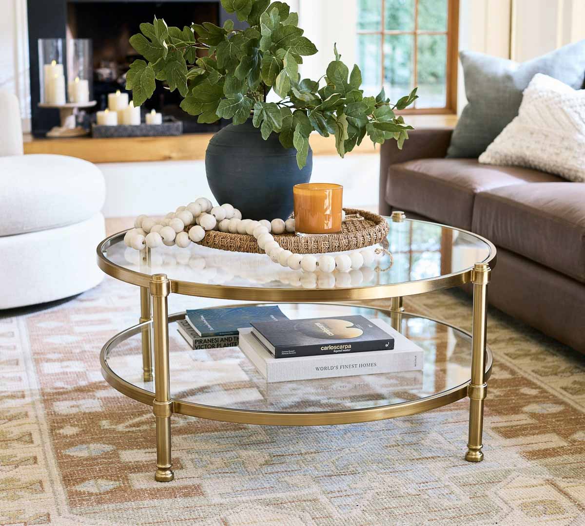 Round woven tray with plant, beads, and candle on round glass coffee table
