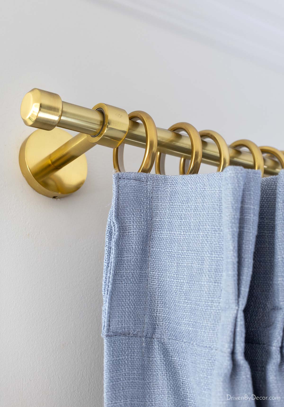 Aged brass curtain rod with dusty blue curtains