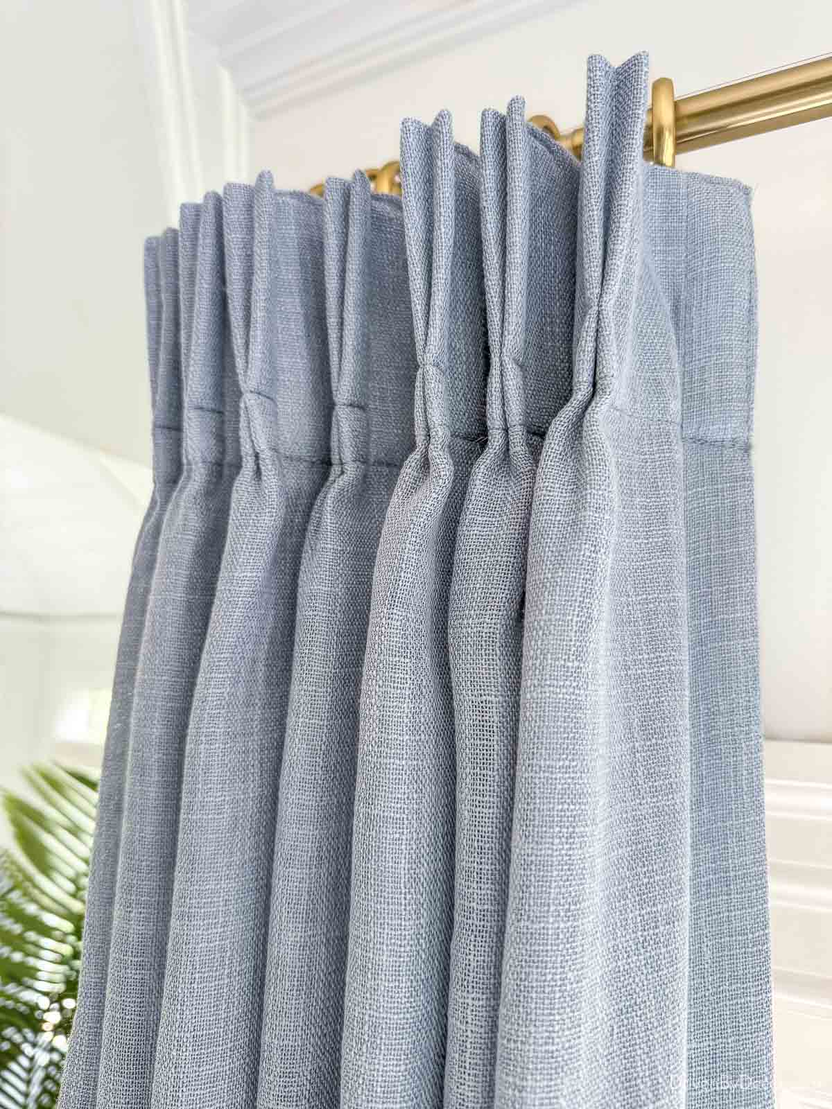 Pleated dusty blue curtains in bay window