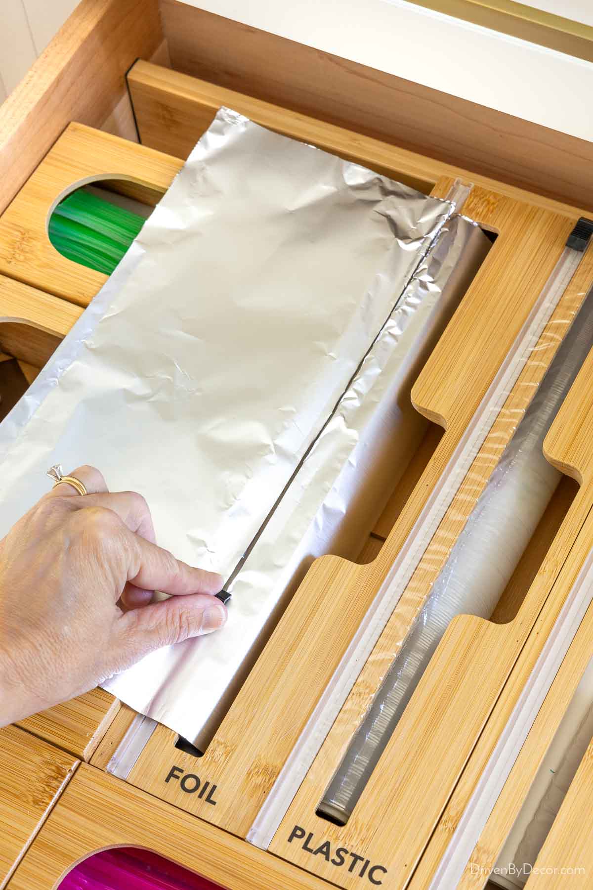 Cutting off aluminum foil from its bamboo drawer organizer