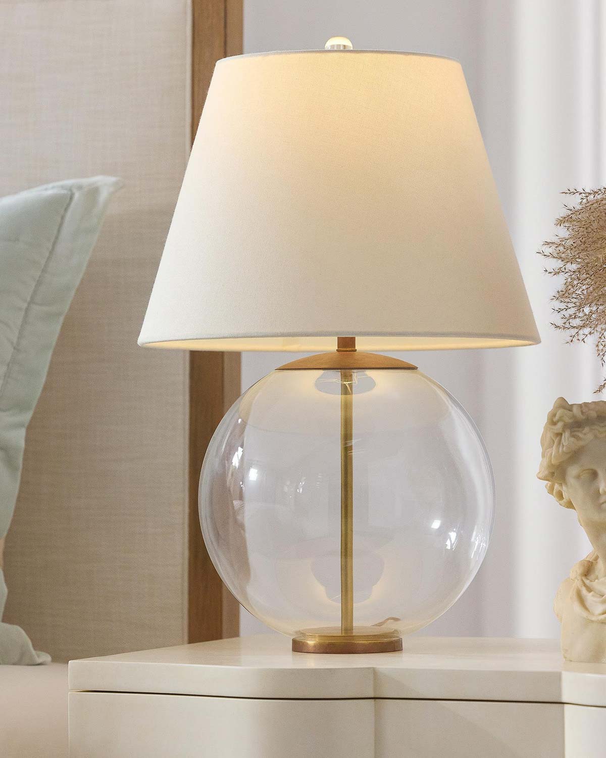 Glass orb lamp with brass details on nightstand