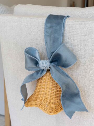 Rattan bells with velvet ribbon on back of chair for coastal Christmas decor