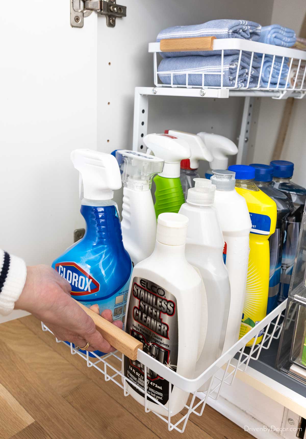 Tiered under sink organizer for kitchen sink cabinet with drawer being pulled out
