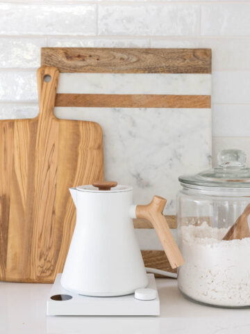 Cutting boards, teapot, and glass jar with flour on kitchen countertop