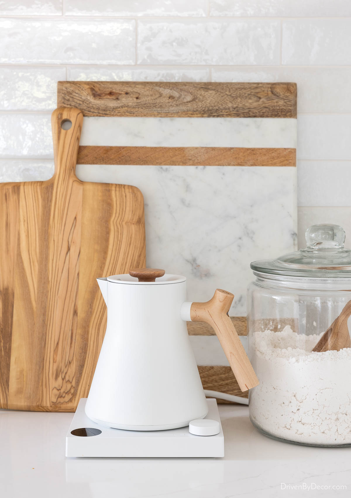 Cutting boards, teapot, and glass jar with flour on kitchen countertop