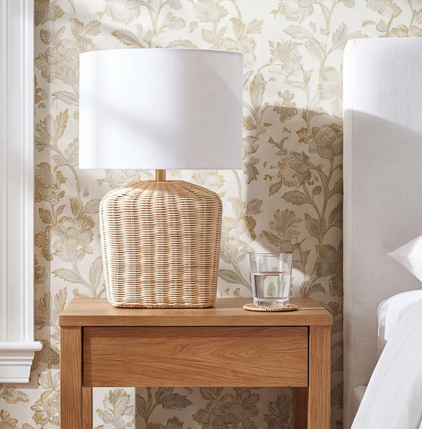 Woven lamp on nightstand next to bed
